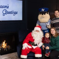 Mom and little boy next to Santa, dad behind chair